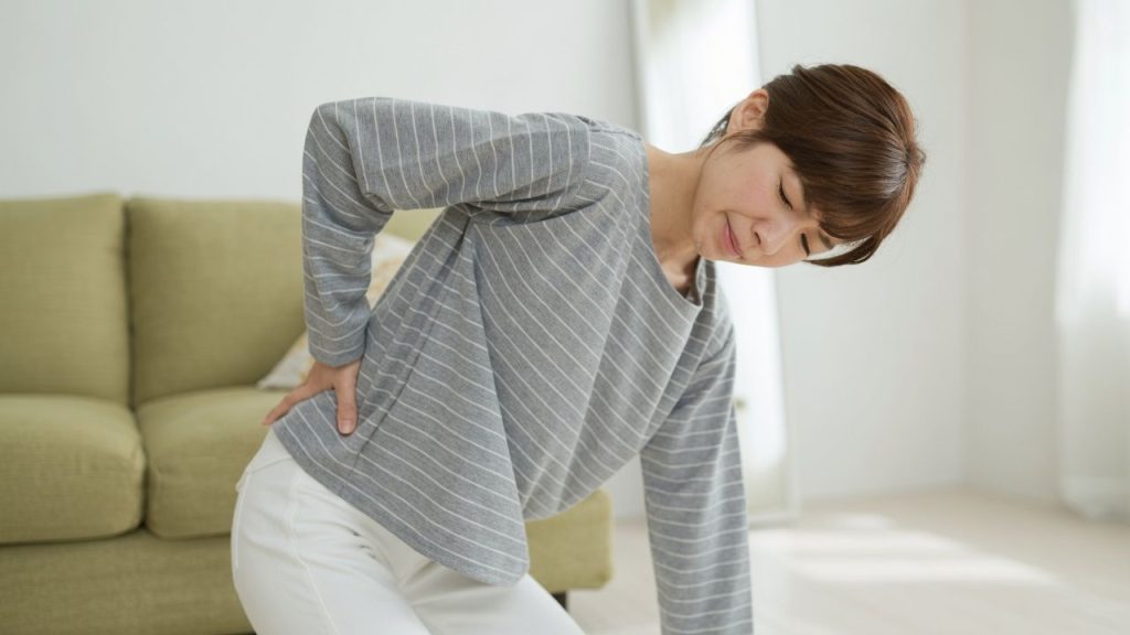腰に手を当てて痛みを感じている女性