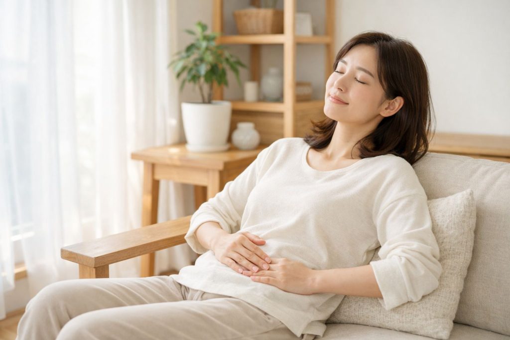 下腹部に手を添えながら、ゆっくり呼吸して休んでいる女性