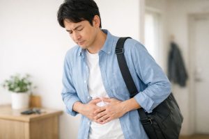 外出前に腹痛を感じてお腹を押さえる男性